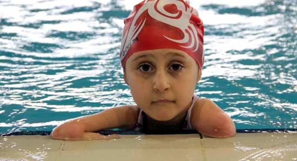 Kolları olmadan yüzüyor, ayaklarıyla resim yapıyor