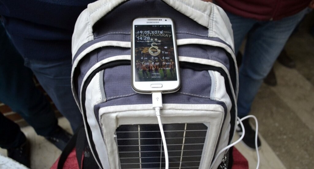Sırt çantasındaki güneş paneliyle telefon şarj ediyor